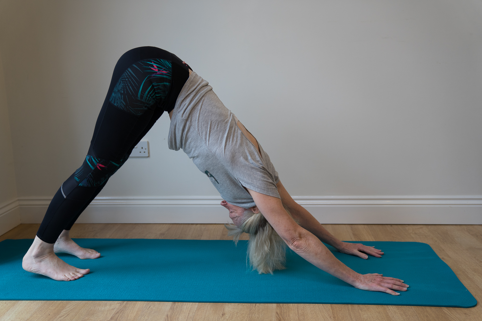 Viv in downward dog on a teal mat